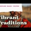 Maasai warrior with vivid red shuka draped over one shoulder — full-length portrait against savanna and acacia background