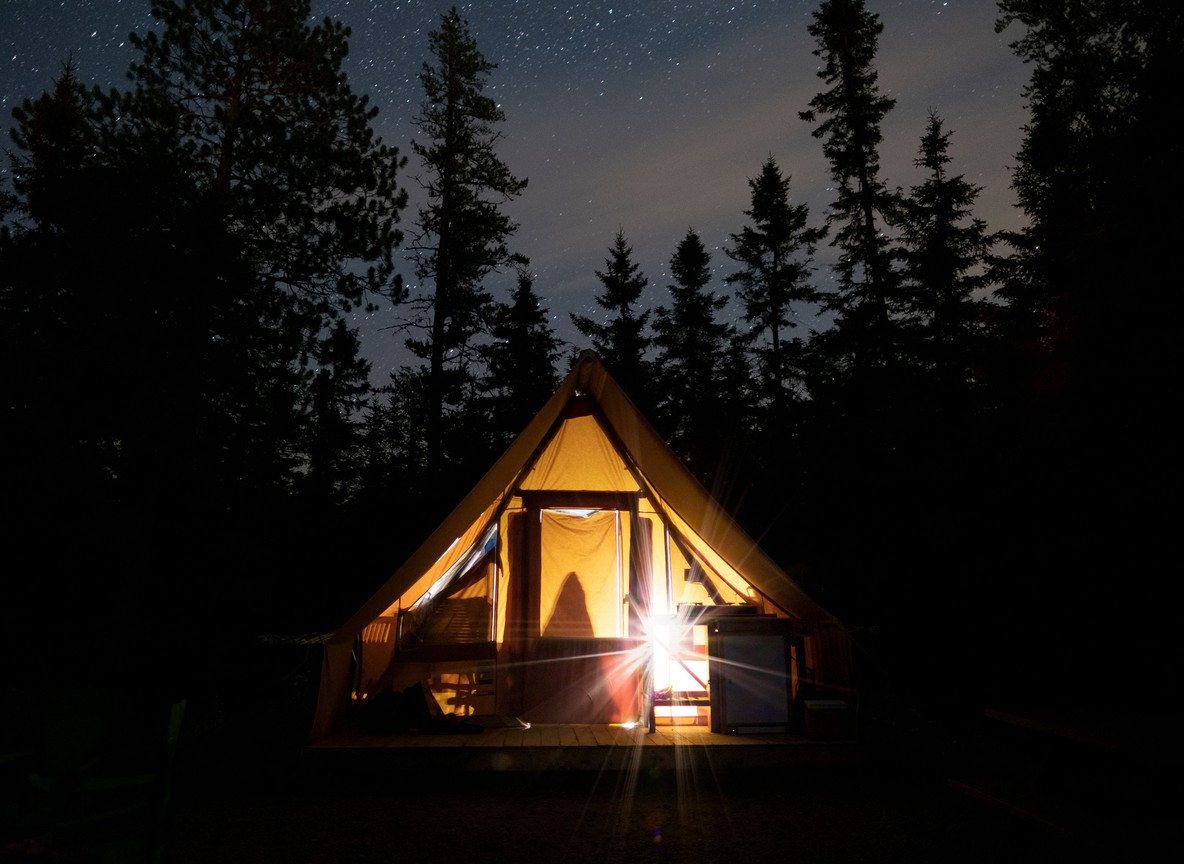 A simple but comfortable safari tent with mosquito netting and a view of grassland at dawn