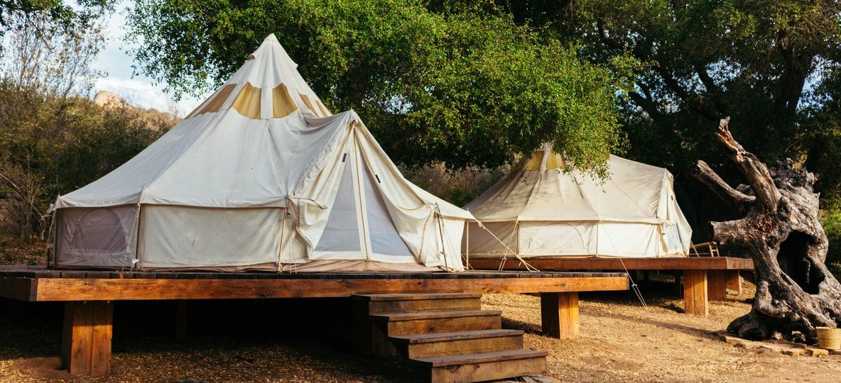 Best Samburu camps Kenya: a tented safari camp on the banks of the Ewaso Nyiro River in Samburu at golden hour, with acacia trees and red-earth hills in the background