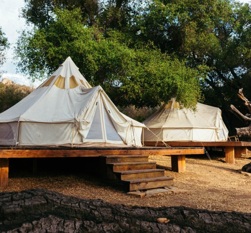 Best Samburu camps Kenya: a tented safari camp on the banks of the Ewaso Nyiro River in Samburu at golden hour, with acacia trees and red-earth hills in the background