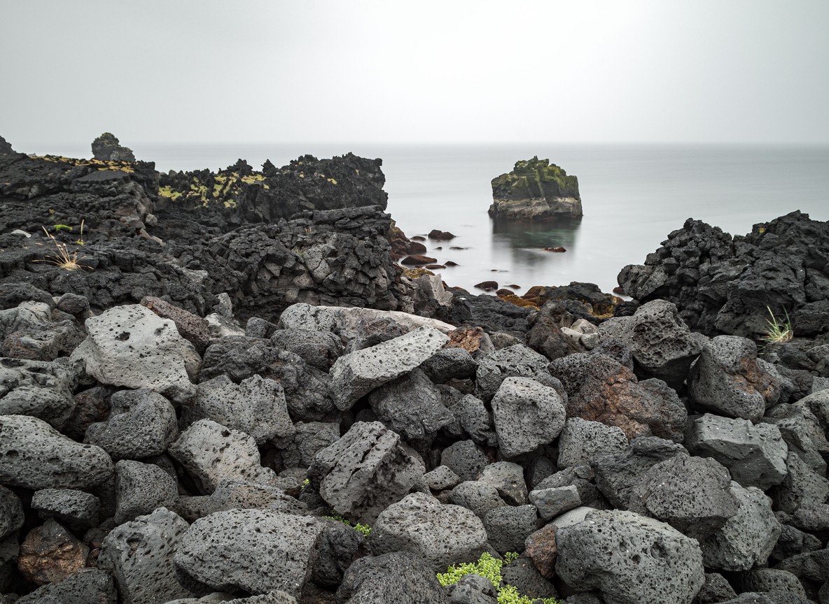 Dark volcanic rock formations along the shoreline near Central Island National Park's crater lakes