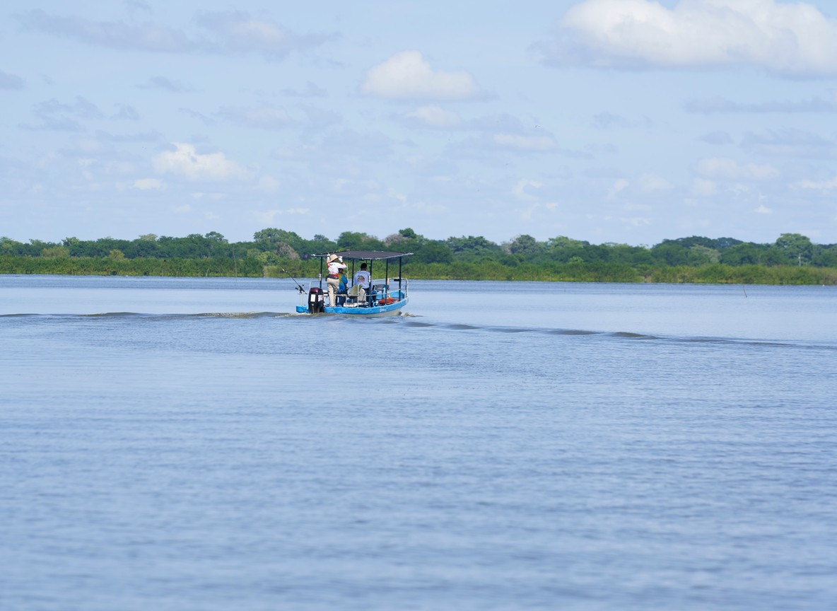 Kenya Wildlife Service rangers preparing a transport crate beside a flatbed truck near a shrinking lake shoreline
