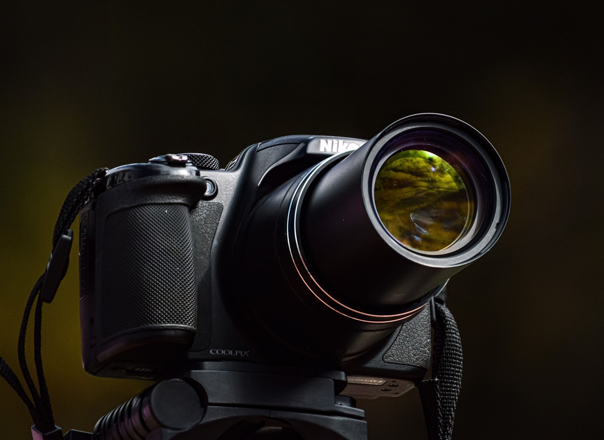 A camera with a telephoto lens and binoculars resting on a safari vehicle window ledge