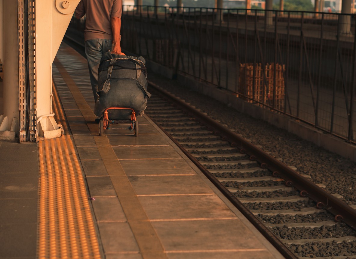 A traveler weighing a packed soft-sided duffel bag on a portable luggage scale