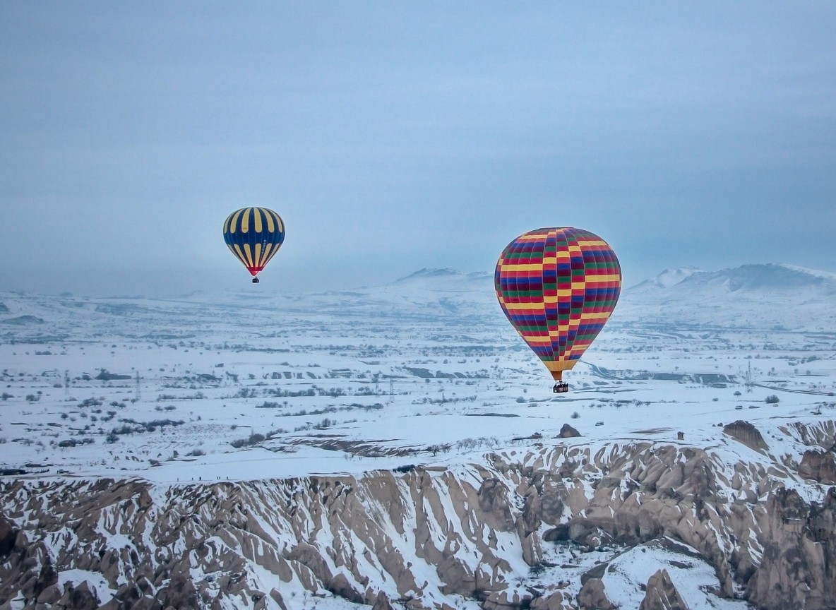 A hot air balloon drifting over green Masai Mara plains at sunrise during the short rains