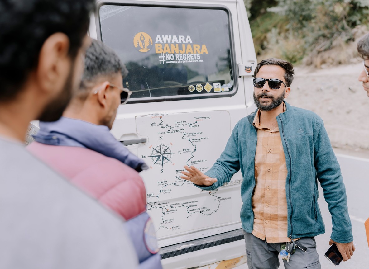 A guide pointing out wildlife behavior to guests from inside a safari vehicle, engines off