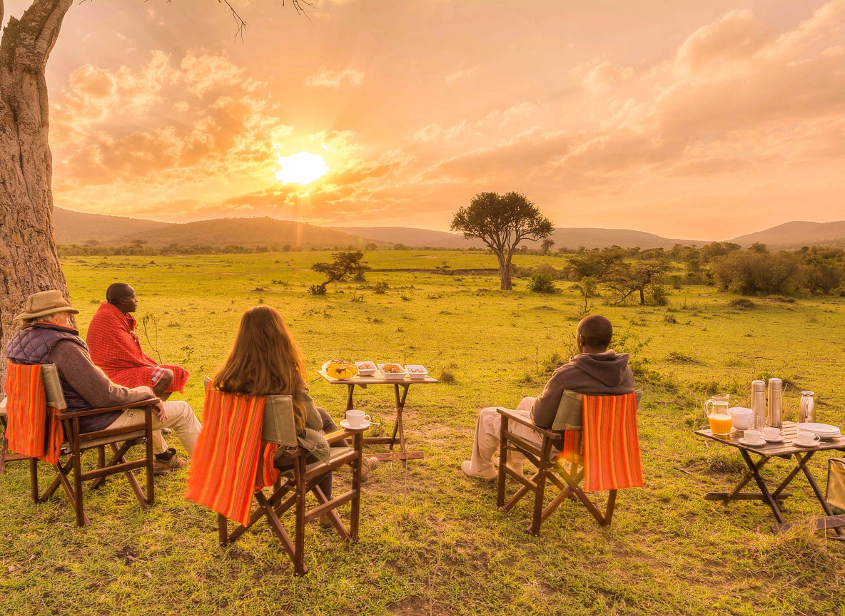 Interior of a budget safari tent with a king size bed, mosquito net, and African furniture near Tsavo East