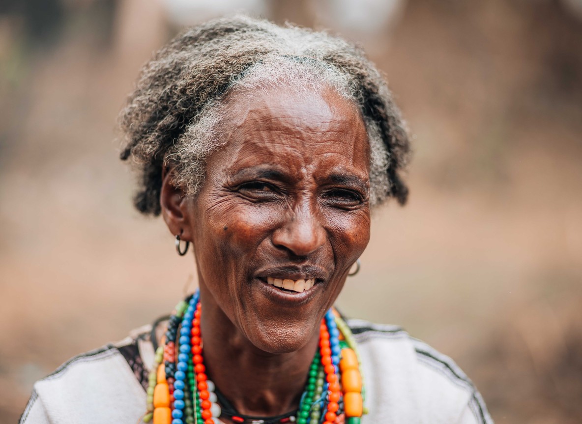 Maasai elder in traditional beaded ornaments sharing stories at a community campsite near the Loita Hills