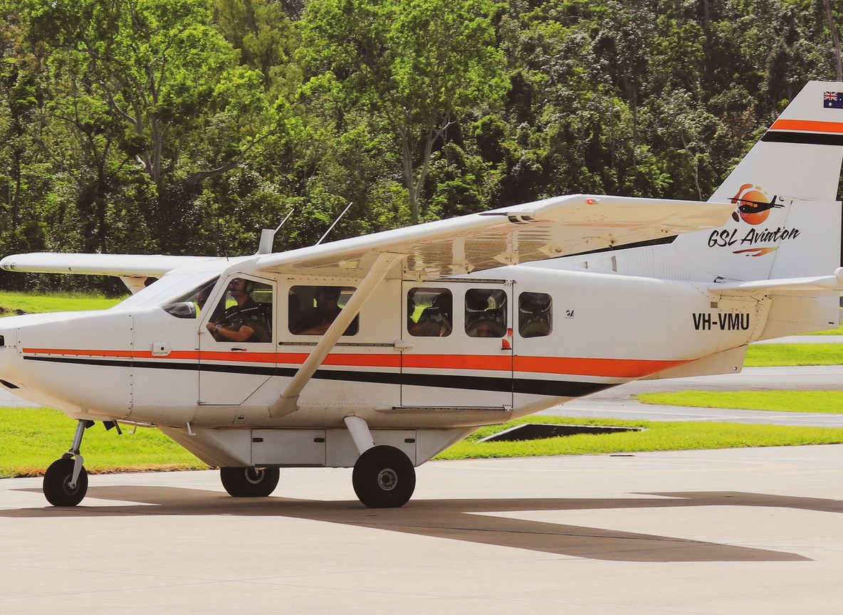 Tourists disembarking a light aircraft at a dusty airstrip near the Mara-Serengeti border with a safari vehicle waiting