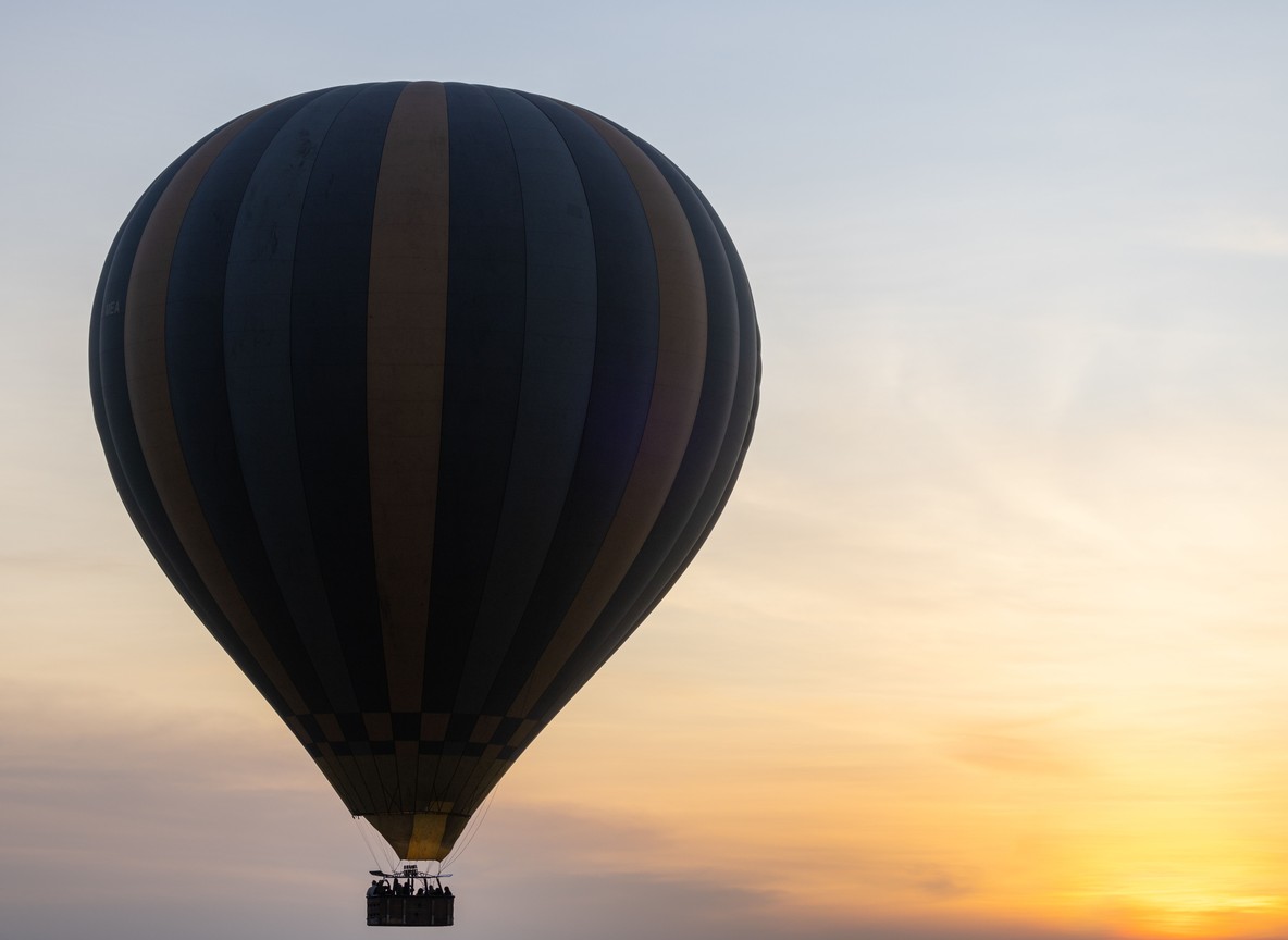 A hot-air balloon drifting over the Masai Mara plains at sunrise