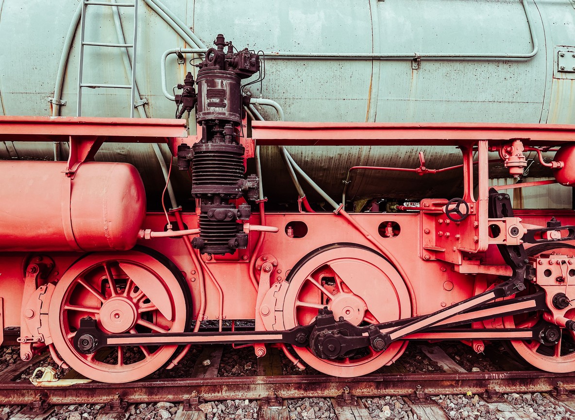 Close-up of a vintage steam locomotive wheel and pistons on display in a railway museum yard