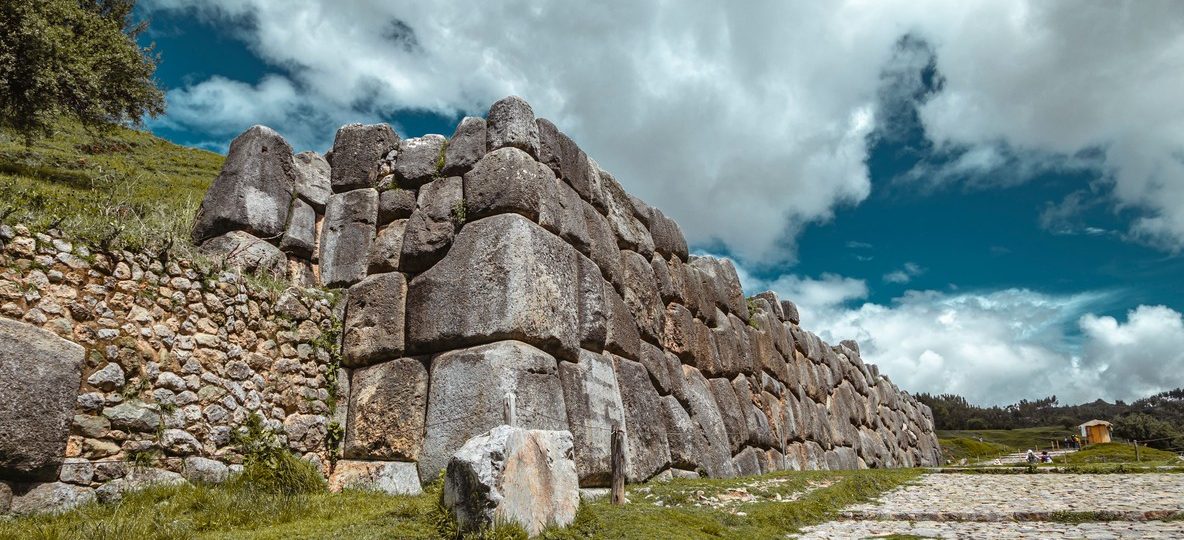 weathered grey stones stacked without mortar, tall grass and acacia trees around the perimeter, soft morning light -- no text overlay, no collage, no multi-panel, no typography, pure photography, single continuous scene
