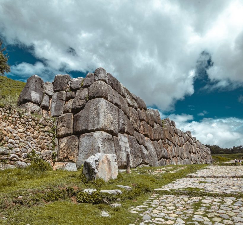 weathered grey stones stacked without mortar, tall grass and acacia trees around the perimeter, soft morning light -- no text overlay, no collage, no multi-panel, no typography, pure photography, single continuous scene