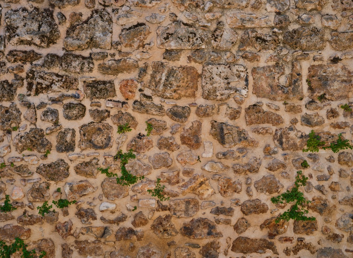 texture of hand-stacked grey stones without mortar, warm afternoon light raking across the surface -- no text overlay, no collage, no multi-panel, no typography, pure photography, single continuous scene