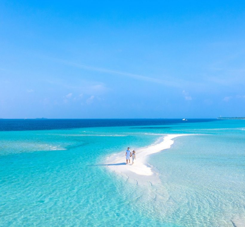 Aerial view of a beachfront resort with palm-lined gardens beside a turquoise coral lagoon on the Watamu coast of Kenya